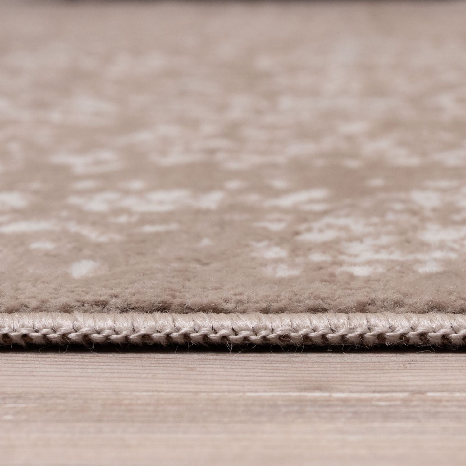 Close-up of a textured beige rug on a wooden floor