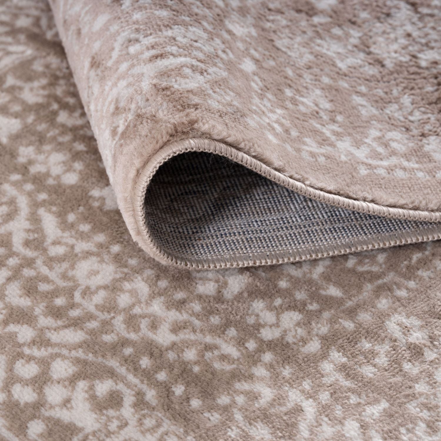 Close-up of a beige patterned rug with a textured surface.